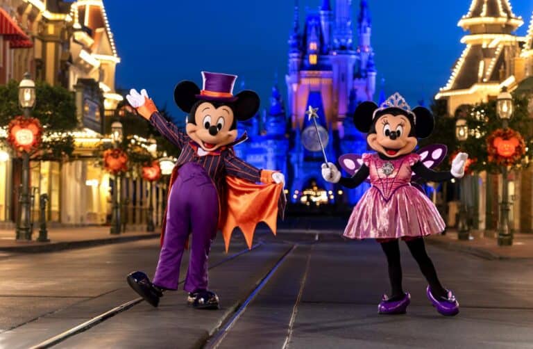 Mickey and Minnie Mouse dressed in Halloween costumes on Main Street USA at Walt Disney World with Cinderella's Castle in background