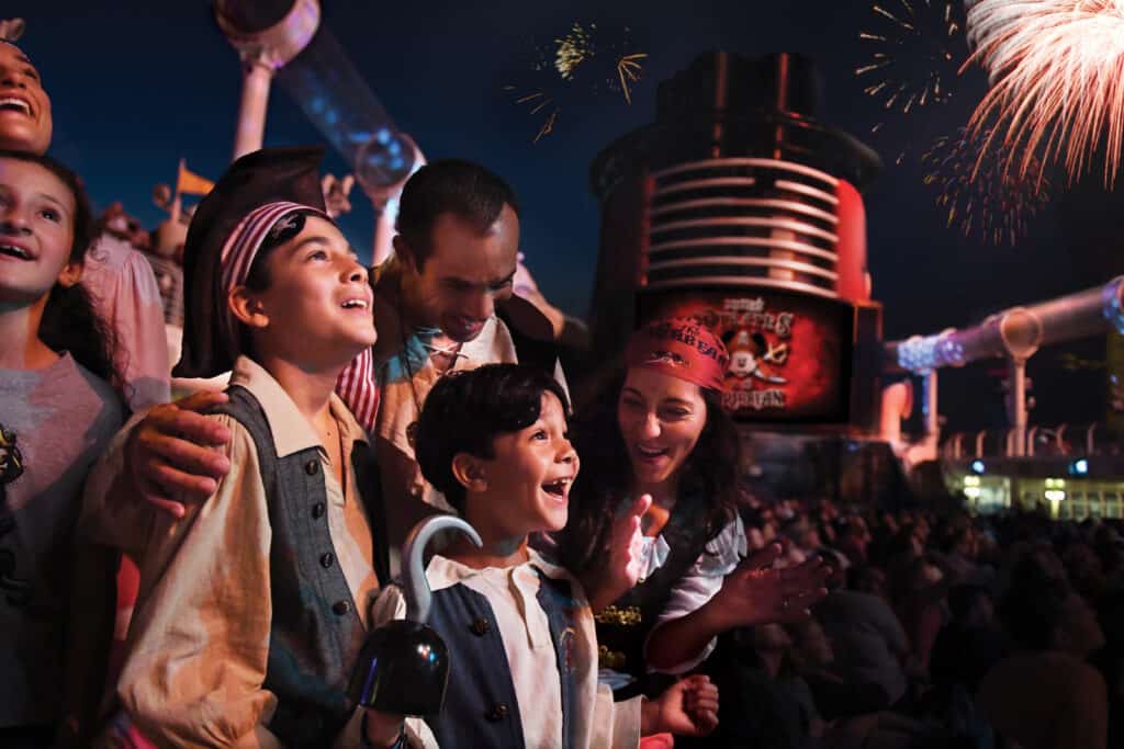 A family dressed a pirates smiling and enjoying Pirate night fireworks o