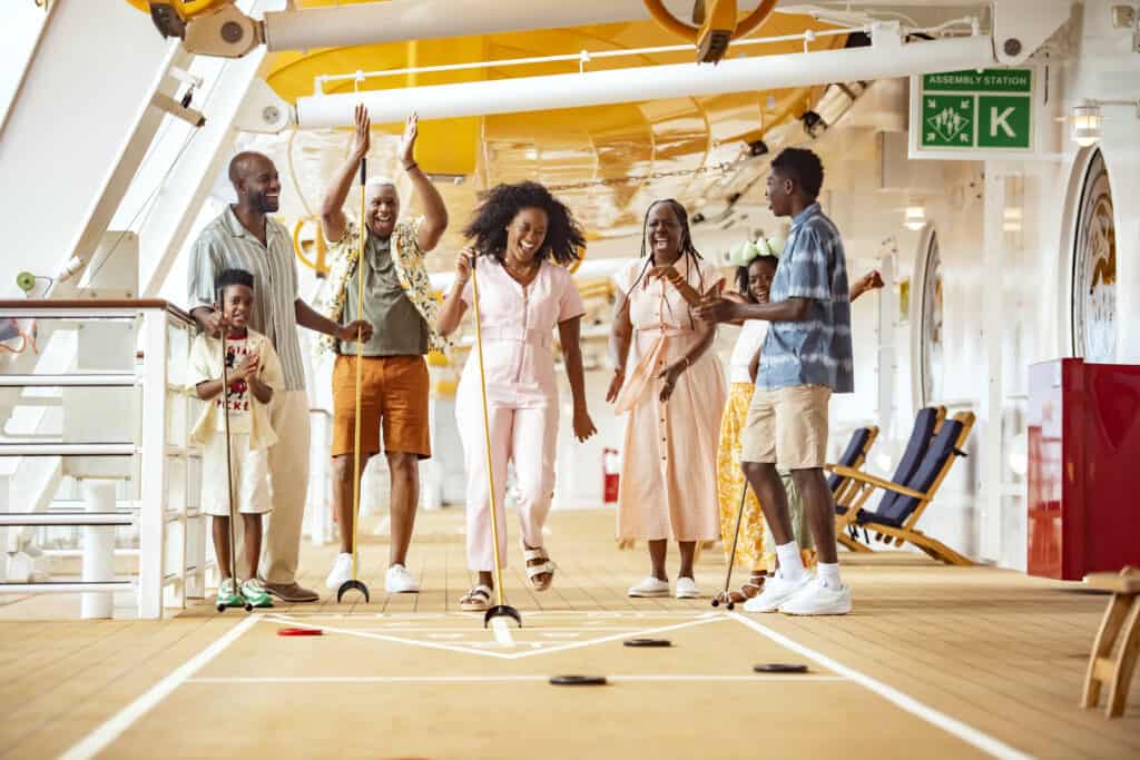Extended family jumping to celebrate a shuffleboard win on the deck of a Disney cruise