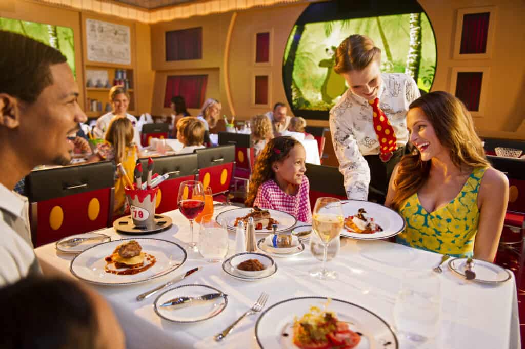 Family sitting at a Disney Cruise rotational dining table being served by a Disney server