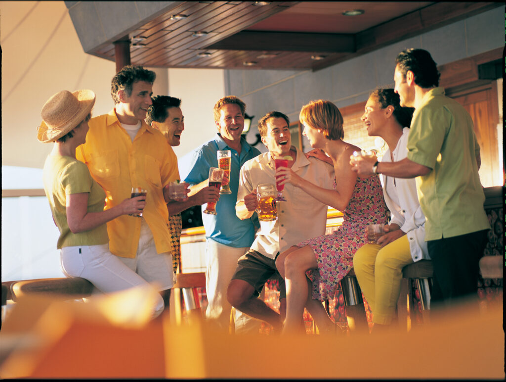 Group of adult friends enjoying drinks on the deck of a Norwegian Cruise ship