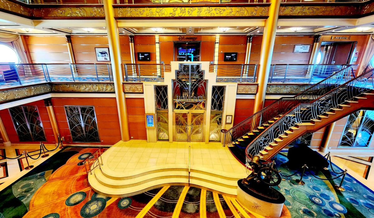 Wide shot of the Disney Cruise Line ship, Disney Magic's Atrium with Mickey statue, stairwell and door to Lumieres and DLounge