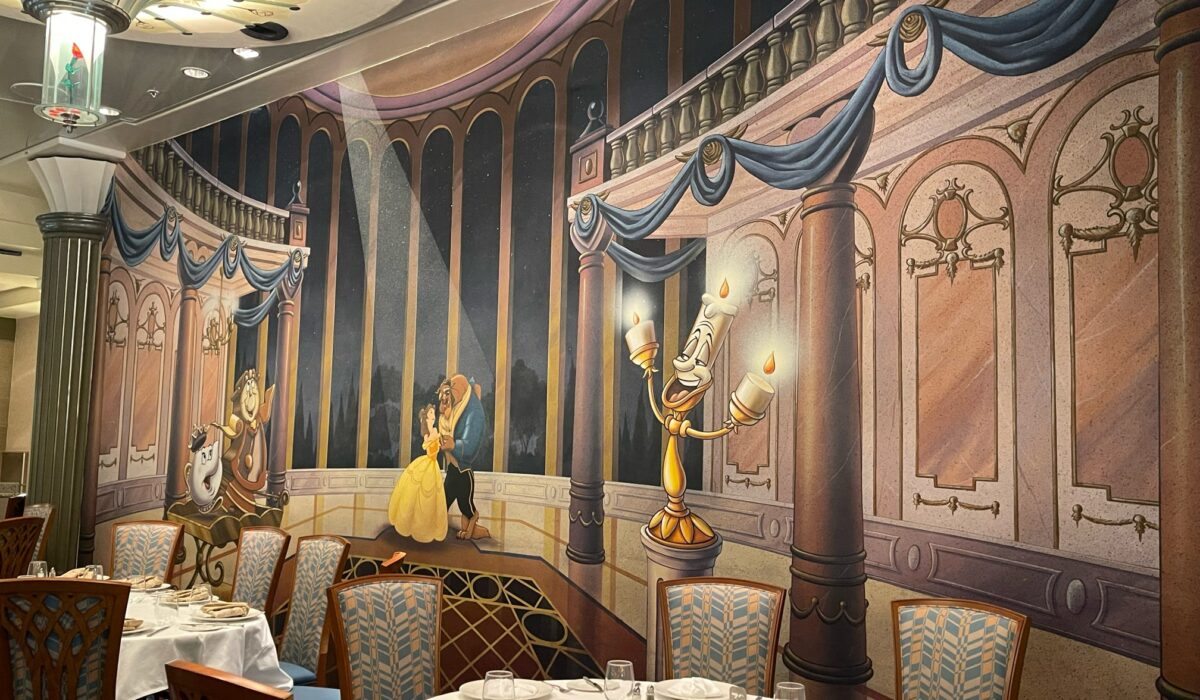 Dining tables set in main dining room with Beauty and the Beast mural in background at the rotational dining restaurant Lumieres on the DCL Disney Magic