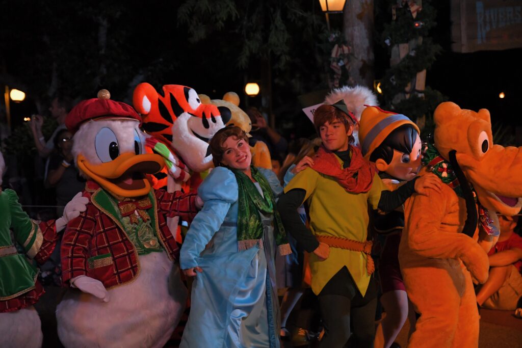 Wendy and Peter Pan with Donald Duck, Pluto and Tigger dressed in holiday attire during the Mickey's Very Merry Christmas Parade in Walt Disney World at night