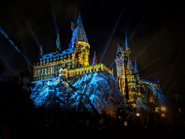 Christmas projections overlaying Hogwarts Castle in the Wizarding World of Harry Potter for Holidays at Universal at night