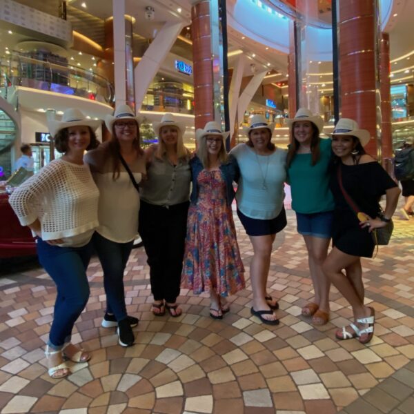 women wearing cowboy hats posing for group picture in the Atrium of Royal Caribbean Cruise Line's Allure of the Seas