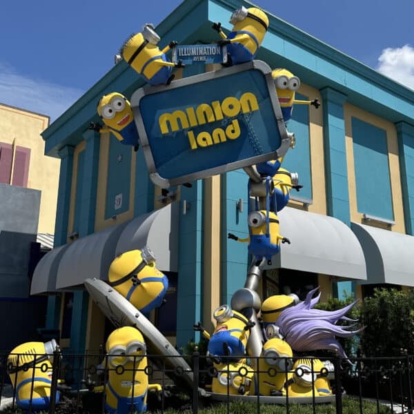 Several yellow Minions stacked up playfully making silly faces in front of the Minion Land sign at Universal Studios Florida