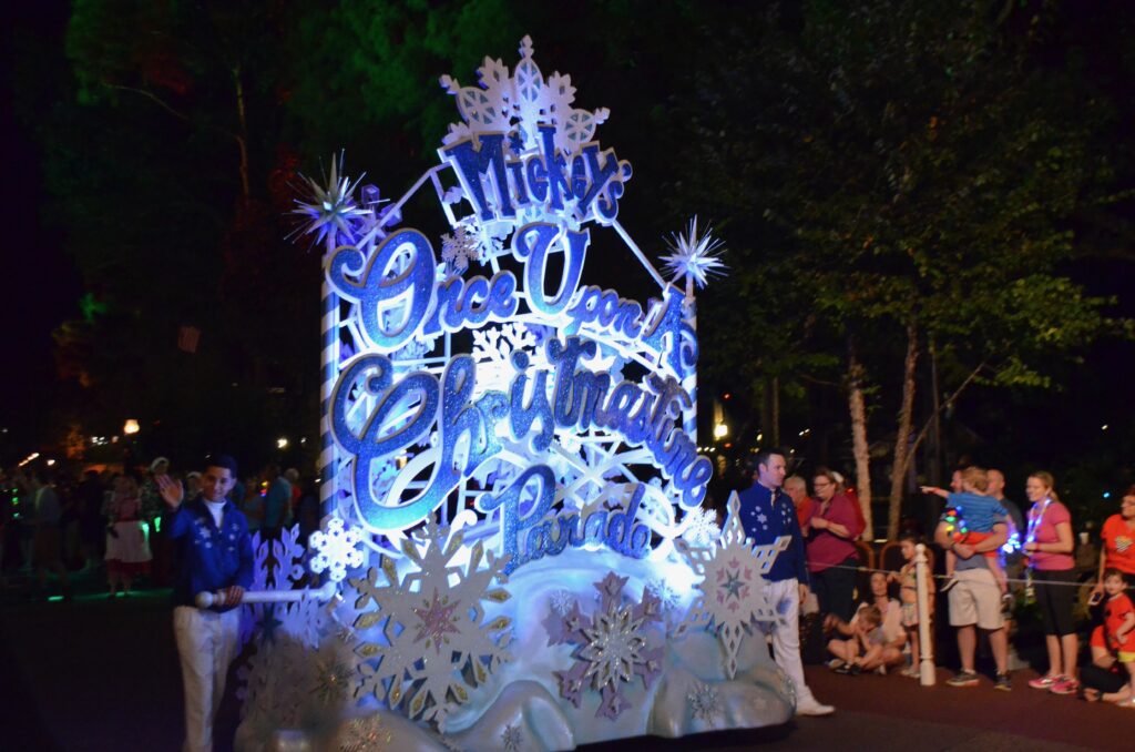 The first float of Mickey's Once Upon a Christmastime Parade at Mickey's Very Merry Christmas Party being escorted by cast members