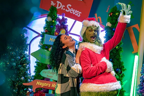 The Grinch interacting with a laughing guest at Grinchmas character meet in Universal Orlando Islands of Adventure