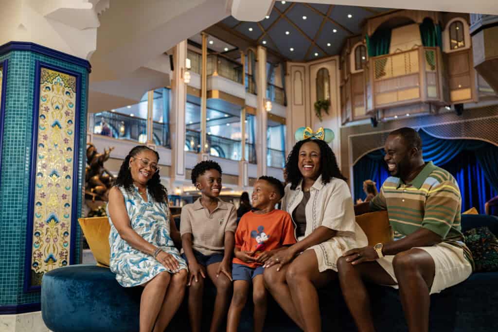 Family sitting on Disney Cruise Line bench in the atrium of the Disney Treasure