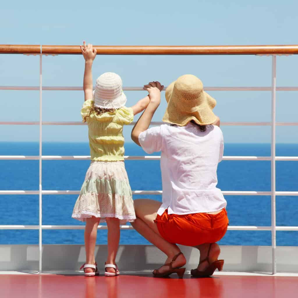 Mom and daughter looking out to sea from cruise deck railing